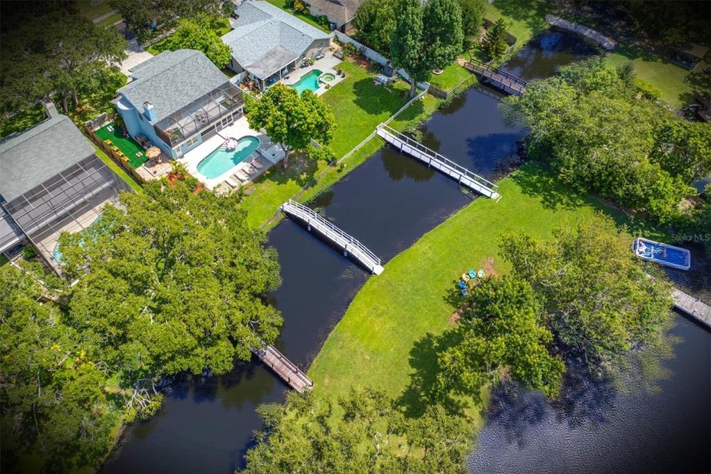 An aerial view shows several houses with swimming pools bordering a narrow canal with bridges — 2153 KARAN WAY, CLEARWATER, FL