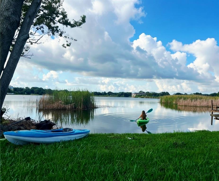 A person paddles a green kayak on a lake near a grassy shore with another kayak — 2153 KARAN WAY, CLEARWATER, FL