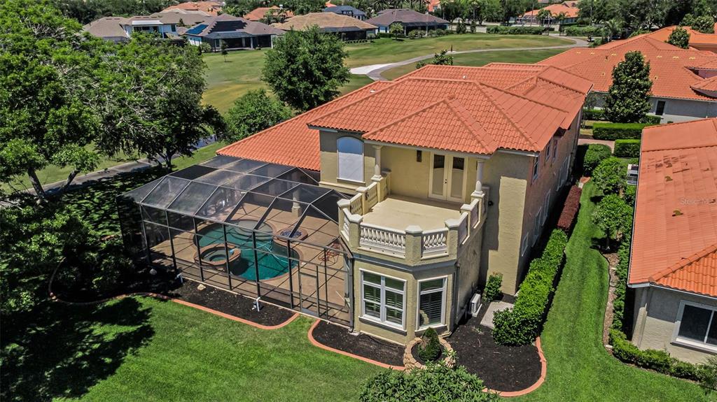 An aerial view of a two-story house with a screened pool and a second-floor balcony — 10706 RUFFINO COURT, TRINITY, FL