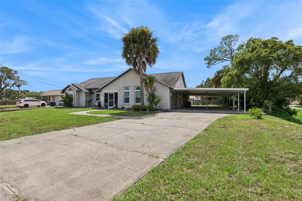 A single-story house with a concrete driveway, a carport, and a palm tree in front — 2504 GLENWOOD DRIVE, EDGEWATER, FL