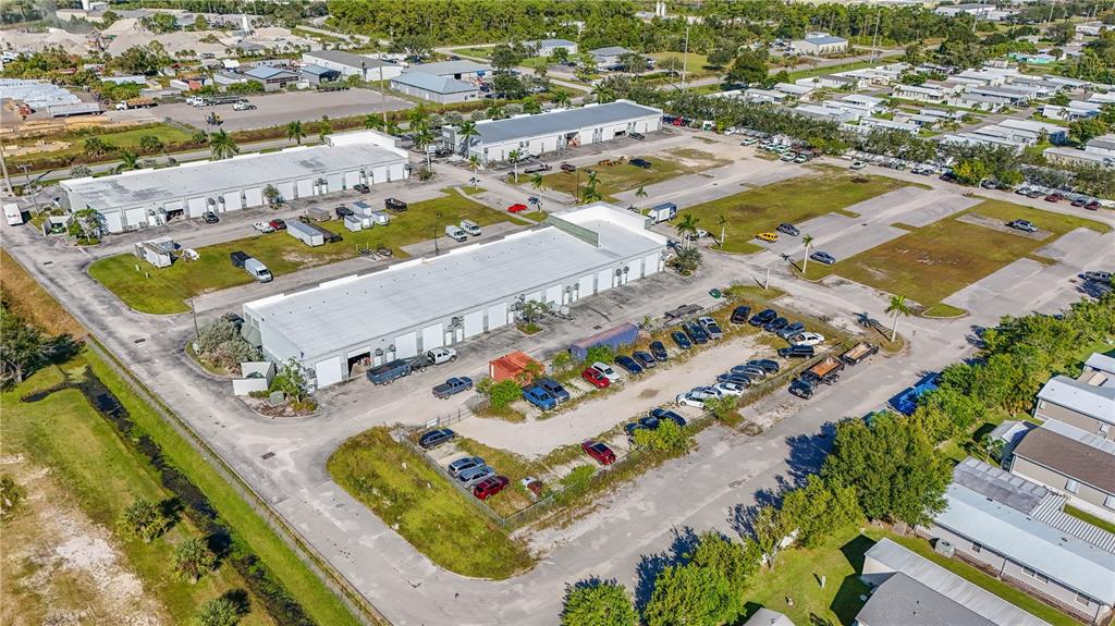 An aerial view shows commercial warehouse buildings surrounded by parking lots and nearby residential homes — 6640 TAYLOR ROAD UNIT B, PUNTA GORDA, FL