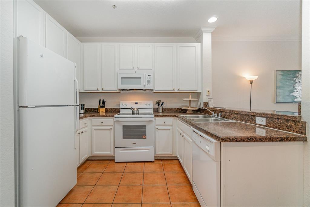 A kitchen with white cabinets, white appliances, brown countertops, and orange tile flooring — 14200 AVALON ROAD UNIT 406, WINTER GARDEN, FL