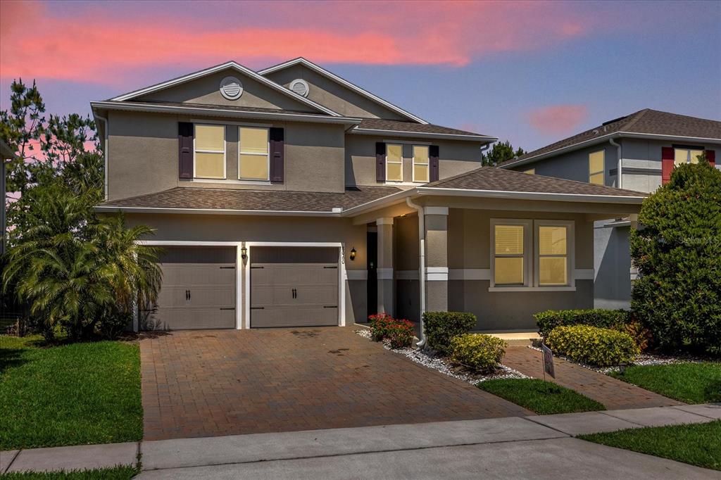 A two-story suburban house with a two-car garage and a paved driveway at sunset — 8060 BOWERY DRIVE, WINTER GARDEN, FL