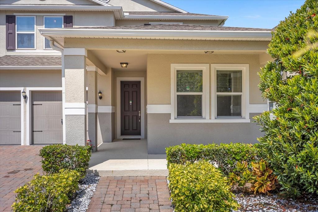 The exterior of a two-story home features a covered entryway, brick walkway, and garage — 8060 BOWERY DRIVE, WINTER GARDEN, FL