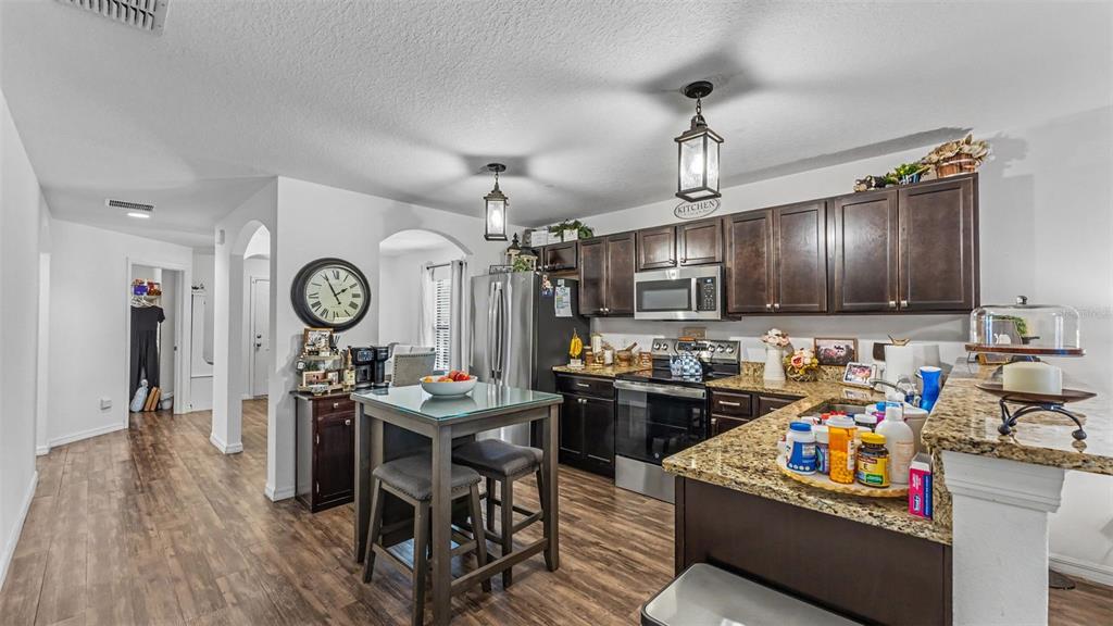 A kitchen features dark wood cabinets, granite countertops, a central island, and wood-look flooring — 6270 MANITOBA DRIVE, LAKELAND, FL