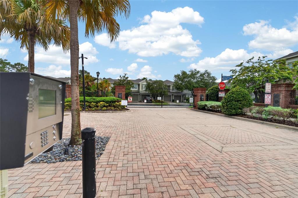 A gated entrance with a keypad, brick-paved driveway, and palm trees leads to townhomes — 2005 RIVER TURIA CIRCLE, RIVERVIEW, FL