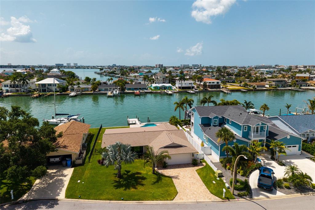 An aerial view shows waterfront homes with docks, swimming pools, and paved driveways — 825 116TH AVENUE, TREASURE ISLAND, FL