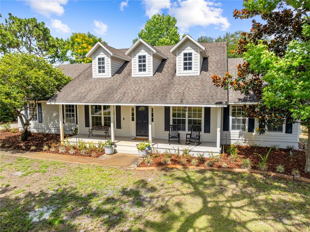 A two-story house with a covered front porch, three dormer windows, and gray siding — 2065 MUSTANG COURT, ST CLOUD, FL