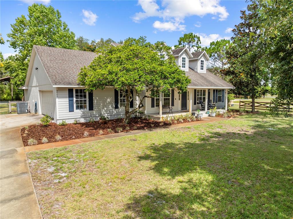 A two-story house with light siding, dark shutters, and a front porch sits on grass — 2065 MUSTANG COURT, ST CLOUD, FL