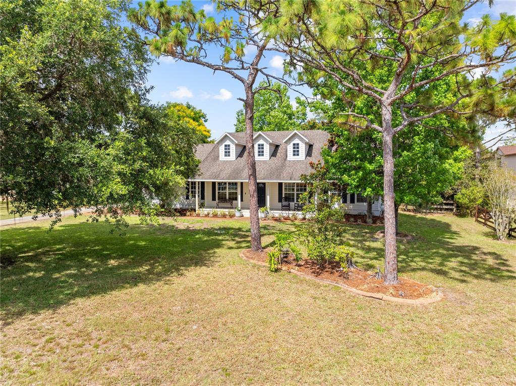 A one-story house with a covered front porch and three dormer windows sits on a lawn — 2065 MUSTANG COURT, ST CLOUD, FL