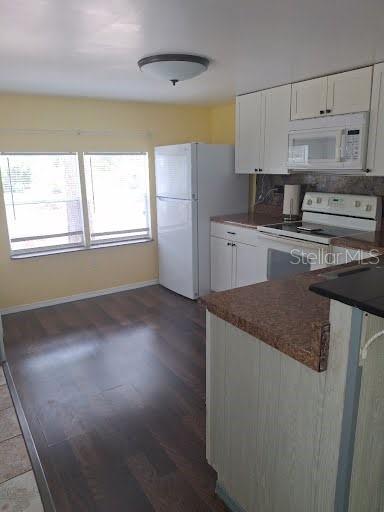 A kitchen features white cabinets, a white refrigerator, a stove, and dark wood-look flooring — 9723 TOM STREET, HUDSON, FL