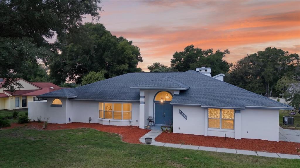 A single-story house with a white stucco exterior, blue front door, and gray shingled roof — 33913 SABAL WAY, LEESBURG, FL