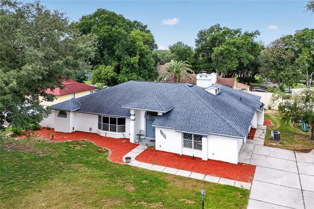An aerial view of a white single-story house with a dark shingled roof and red mulch — 33913 SABAL WAY, LEESBURG, FL