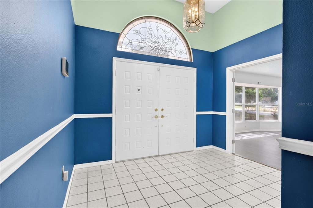 A foyer with white tile flooring, blue walls, and a double door with a transom window — 33913 SABAL WAY, LEESBURG, FL