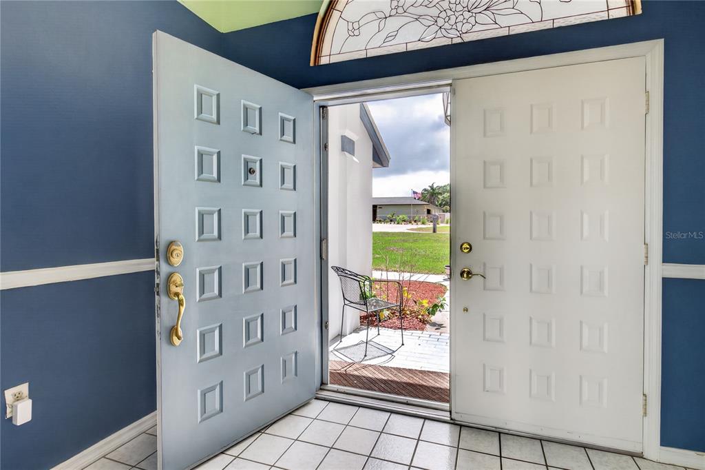 An open double front door reveals a tiled entryway looking out onto a residential yard — 33913 SABAL WAY, LEESBURG, FL