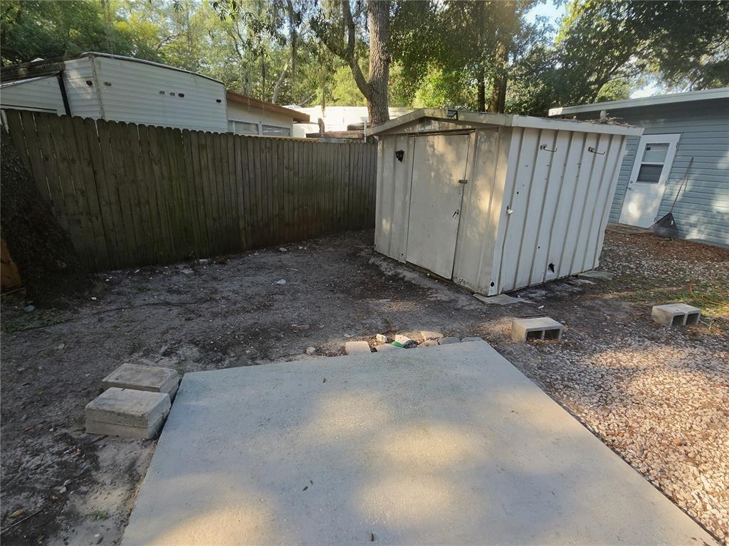 A backyard features a concrete pad, a metal storage shed, and a wooden privacy fence — 3000 CLARCONA ROAD UNIT 244, APOPKA, FL