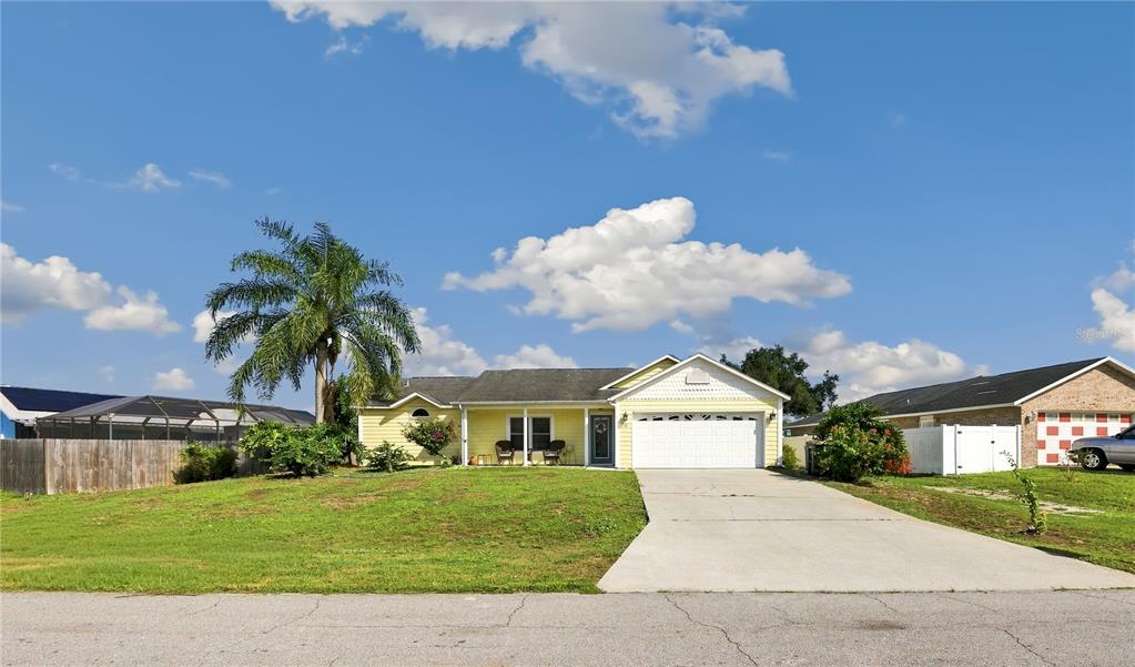 A yellow single-story house with a white garage and a palm tree in the front yard — 181 HAMMOCK ROAD SE, PALM BAY, FL