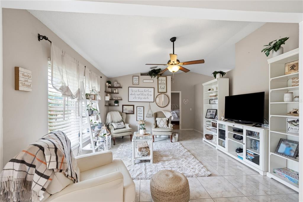 A living room features tile floors, a ceiling fan, white shelving, and two armchairs — 181 HAMMOCK ROAD SE, PALM BAY, FL