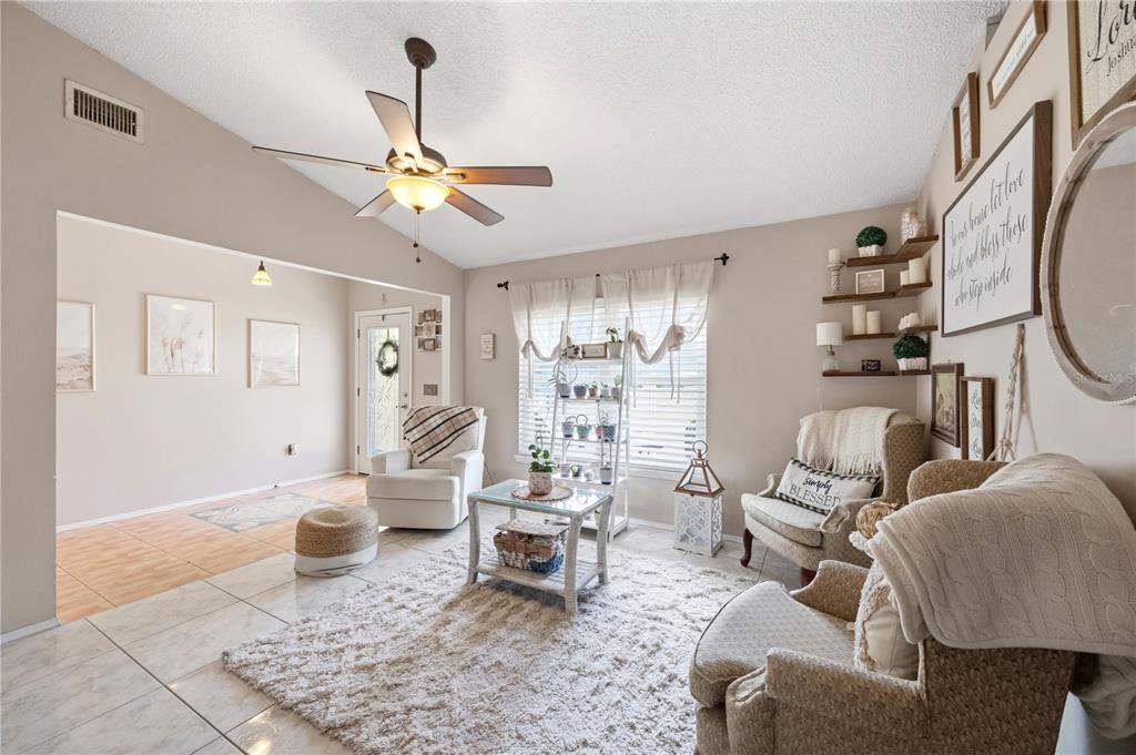 A living room features tile flooring, a ceiling fan, a rug, and several armchairs — 181 HAMMOCK ROAD SE, PALM BAY, FL