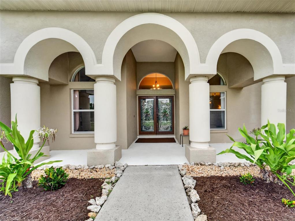 A front entryway features a concrete walkway leading to double doors under arched stucco columns — 13020 SHADOW RUN BOULEVARD, RIVERVIEW, FL