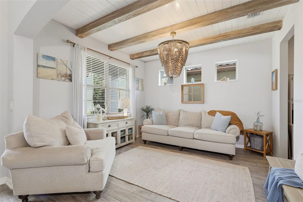 A living room features a beaded chandelier, wood ceiling beams, and a paneled accent wall — 285 ANCONA AVENUE, DEBARY, FL
