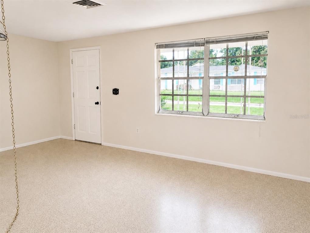 An empty room with beige walls, a white door, and a window with grid panes — 3519 BROOKSTON DRIVE, HOLIDAY, FL