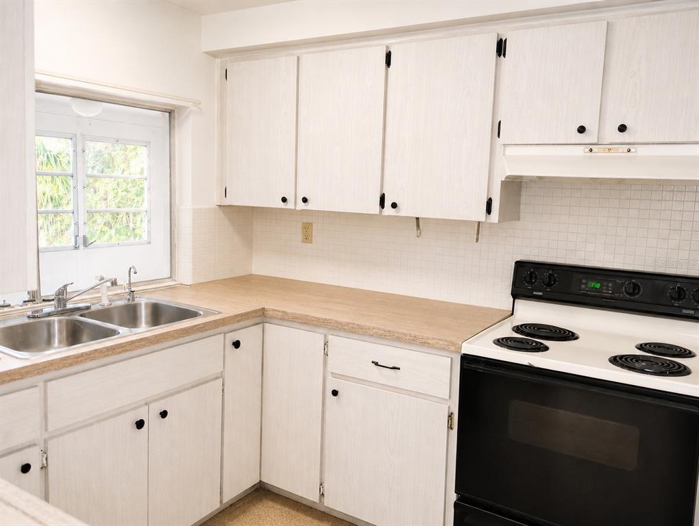 A kitchen features white wood-grain cabinets, a laminate countertop, a double sink, and a stove — 3519 BROOKSTON DRIVE, HOLIDAY, FL
