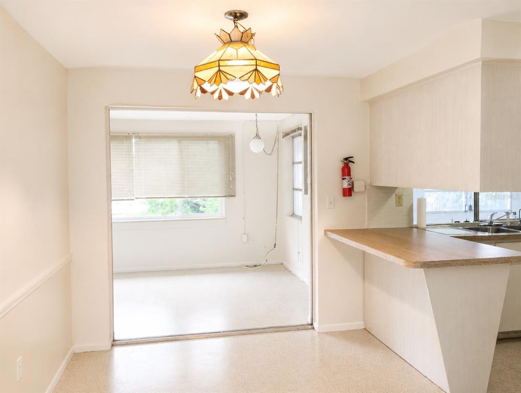 A kitchen with a breakfast bar opens into a sunroom featuring a stained-glass light fixture — 3519 BROOKSTON DRIVE, HOLIDAY, FL