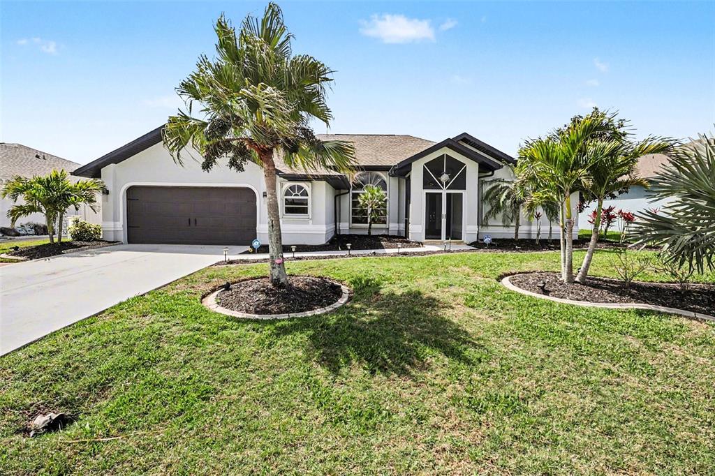 A single-story house with a two-car garage, palm trees, and a landscaped front lawn — 301 GOLD TREE, PUNTA GORDA, FL