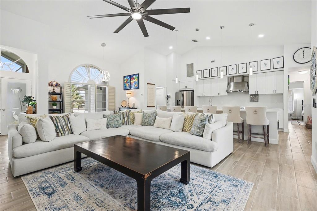 A bright, open-concept living room and kitchen featuring a large sectional sofa and island seating — 301 GOLD TREE, PUNTA GORDA, FL