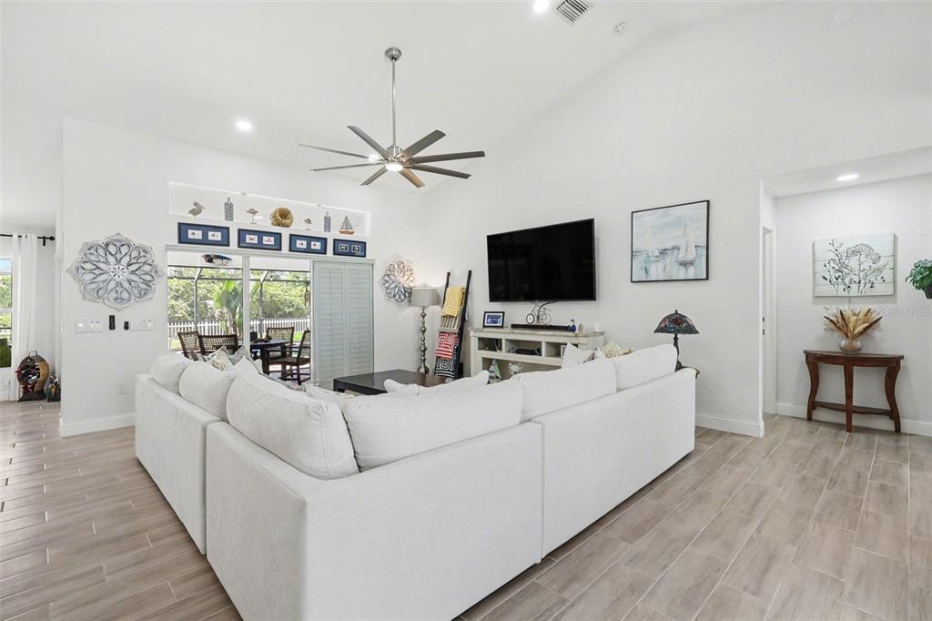 A bright living room features a large white sectional sofa, vaulted ceilings, and tile flooring — 301 GOLD TREE, PUNTA GORDA, FL