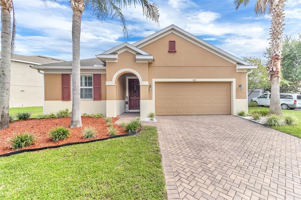 A tan single-story house features a paved driveway, a two-car garage, and two palm trees — 683 CHAMPIONS GATE BOULEVARD, DELAND, FL