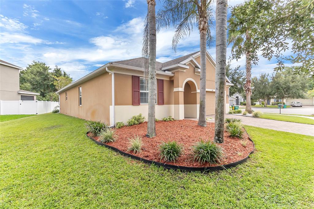 A single-story house with a tan stucco exterior, red shutters, and palm trees in front — 683 CHAMPIONS GATE BOULEVARD, DELAND, FL