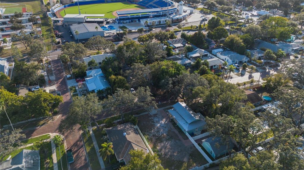 An aerial view shows a residential neighborhood with houses, trees, and a nearby baseball stadium — 448 LOCKLIE STREET, DUNEDIN, FL