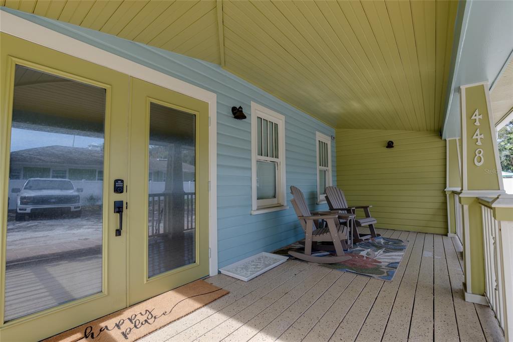 A covered porch features light blue siding, a yellow ceiling, and two wooden rocking chairs — 448 LOCKLIE STREET, DUNEDIN, FL