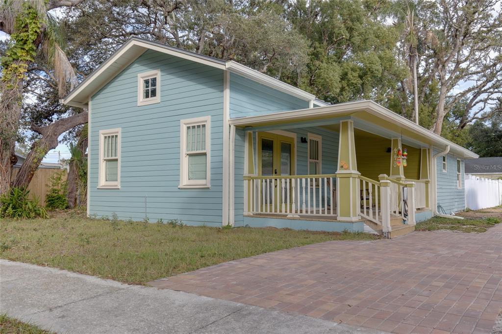 A light blue house with a covered front porch and a brick paver driveway — 448 LOCKLIE STREET, DUNEDIN, FL