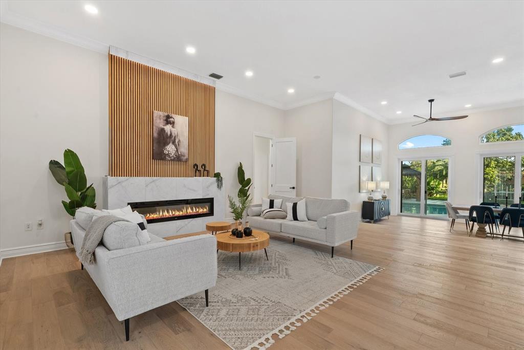 A living room features a marble fireplace with wood slat wall paneling and light flooring — 1707 CARIBBEAN DRIVE, SARASOTA, FL