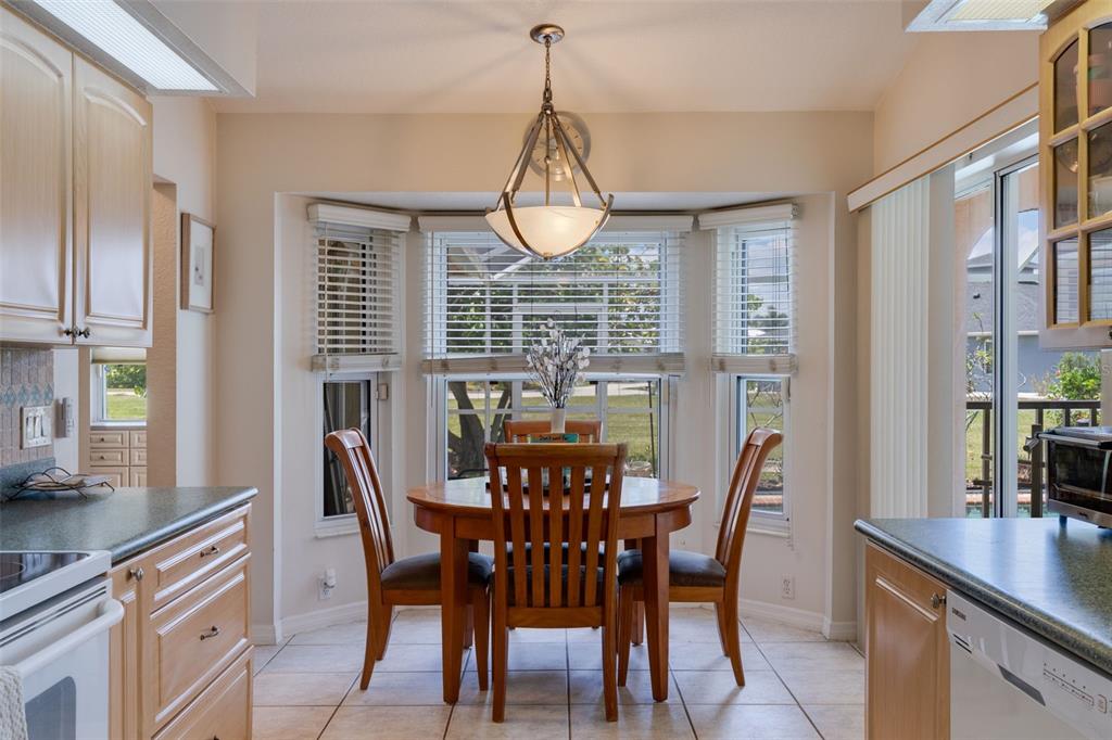 A breakfast nook with a round wooden table, three chairs, and a bay window — 154 ACALYPHA, PUNTA GORDA, FL