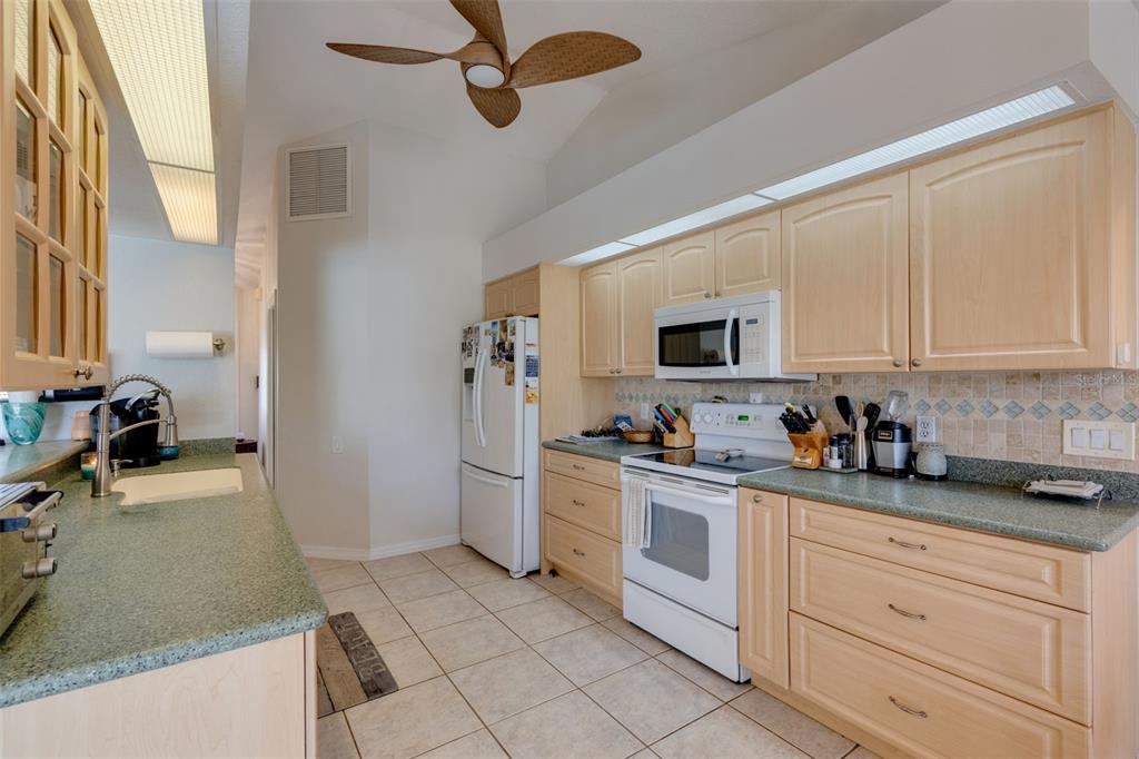 A kitchen with light wood cabinets, green countertops, white appliances, and a ceiling fan — 154 ACALYPHA, PUNTA GORDA, FL