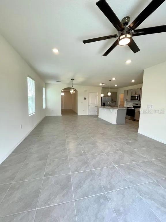 An open-concept kitchen and living area feature light gray tile flooring and a ceiling fan — 8358 HARDY BAY LOOP, WESLEY CHAPEL, FL
