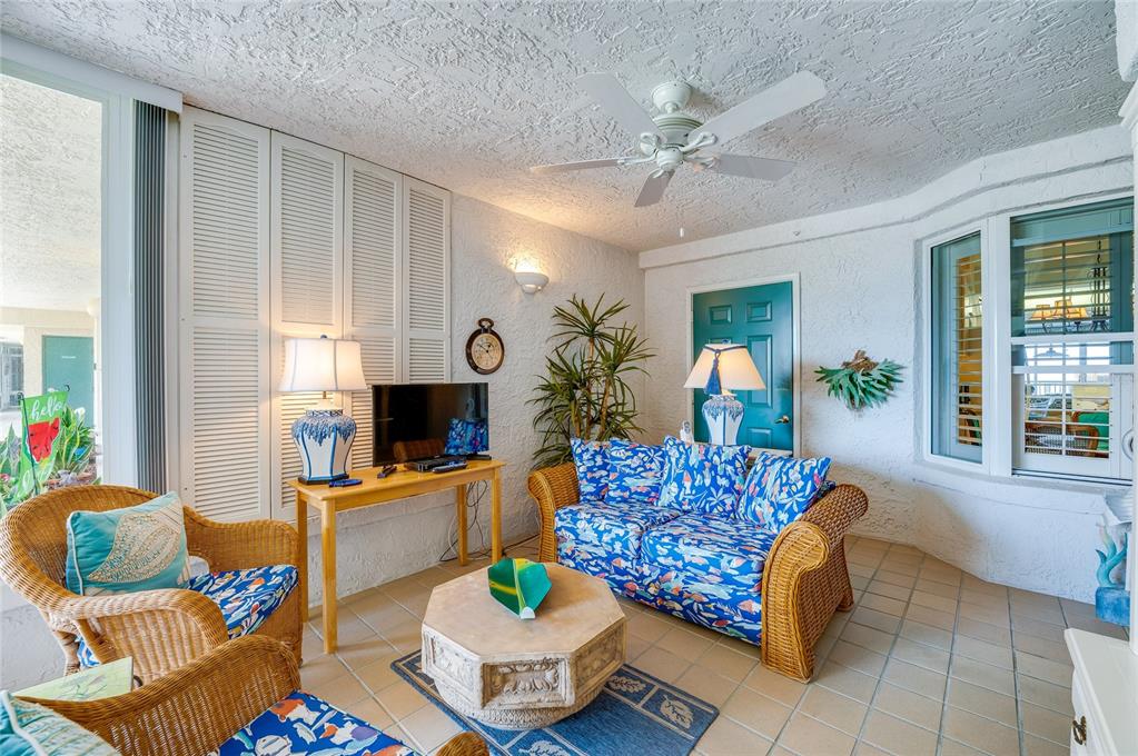 A sunroom features wicker furniture, blue patterned cushions, a tiled floor, and a ceiling fan — 4565 S ATLANTIC AVENUE UNIT 5308, PONCE INLET, FL
