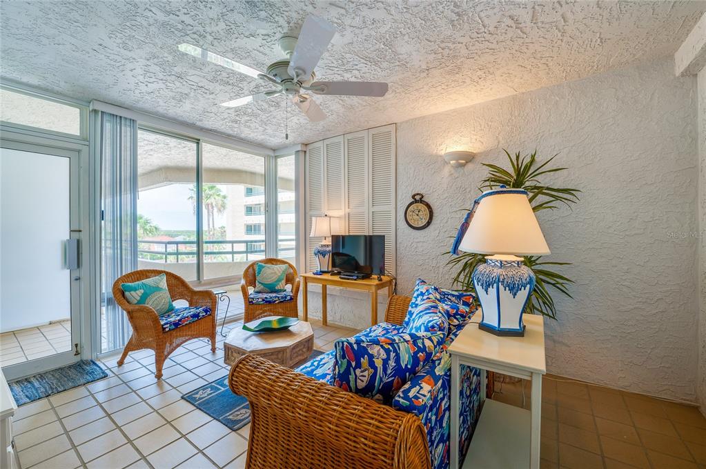 A sunroom features wicker furniture, a blue patterned sofa, tile floors, and a ceiling fan — 4565 S ATLANTIC AVENUE UNIT 5308, PONCE INLET, FL