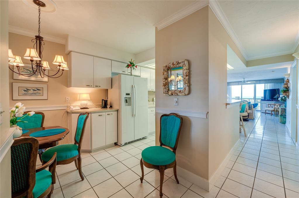 A dining area with teal chairs and a kitchen with white cabinets and tile flooring — 4565 S ATLANTIC AVENUE UNIT 5308, PONCE INLET, FL