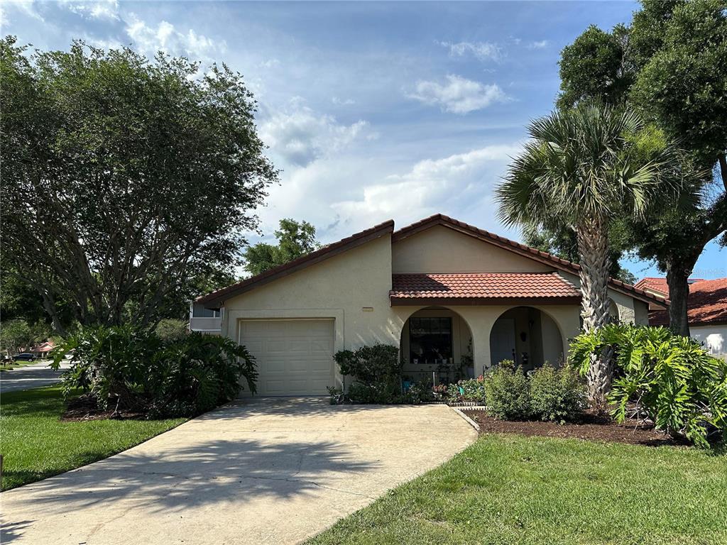 A single-story house with a tan stucco exterior, a tile roof, and a concrete driveway — 6609 EDGEWORTH DRIVE, ORLANDO, FL