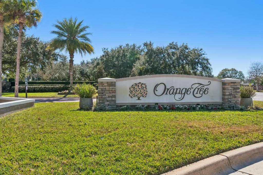 A stone and stucco monument sign for the Orange Tree community stands on a lawn — 6609 EDGEWORTH DRIVE, ORLANDO, FL