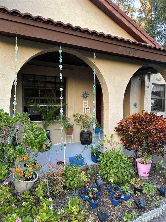 A house exterior features a covered porch with hanging beaded decorations and potted plants — 6609 EDGEWORTH DRIVE, ORLANDO, FL