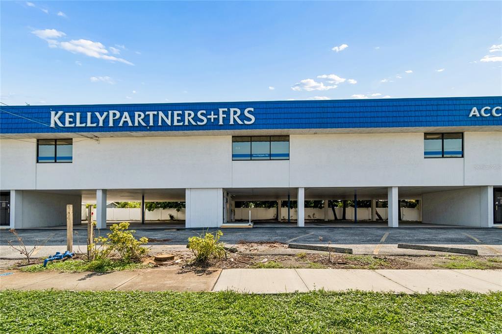 A two-story commercial building features a blue facade, upper-level windows, and a covered parking area — 1301 66TH STREET N, ST PETERSBURG, FL
