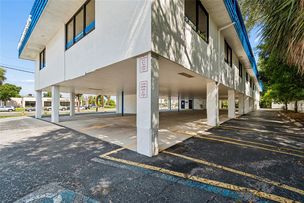 A white commercial building features a covered ground-level parking area supported by concrete pillars — 1301 66TH STREET N, ST PETERSBURG, FL