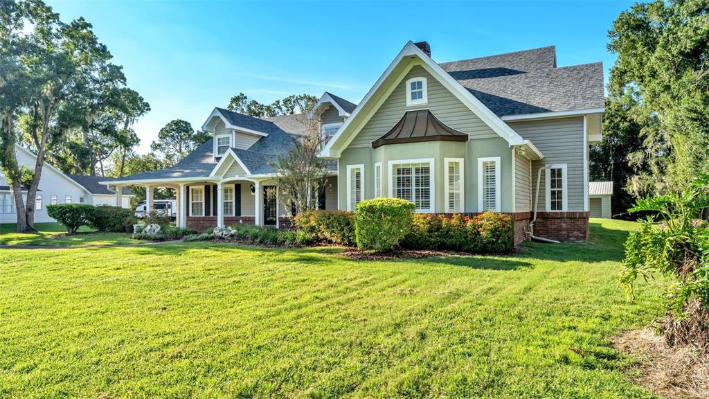 A two-story house with light green siding, a brick base, and a large front lawn — 4233 HOMEWOOD LANE, LAKELAND, FL