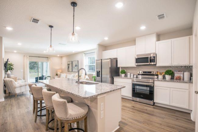 A kitchen with white cabinets, granite countertops, and an island with bar seating — 620 BROADOAK DRIVE, DUNDEE, FL